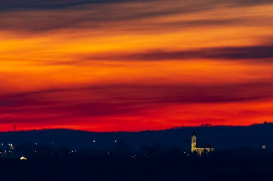 Vöröslő égbolt és a sormási templom Nagykanizsáról fotózva naplemente után.